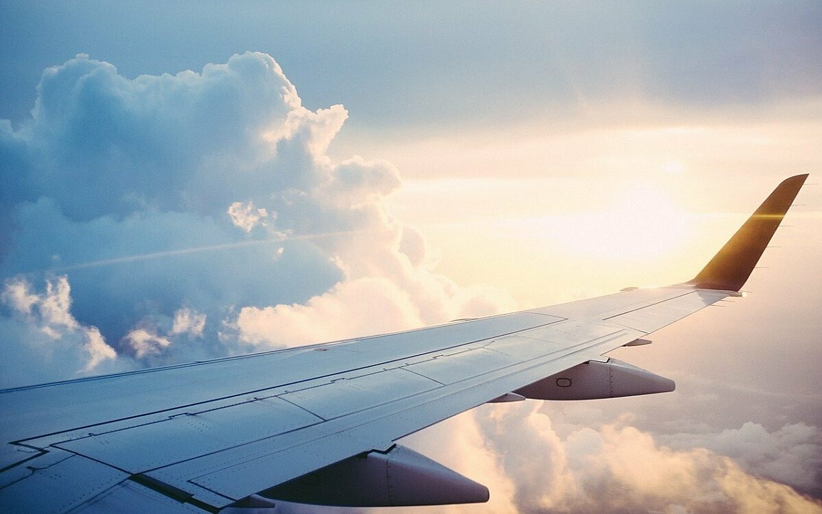 Die Tragfläche eines Flugzeugs vor der Sonne am Himmel und Wolken Die Tragfläche eines Flugzeugs vor der Sonne am Himmel und Wolken